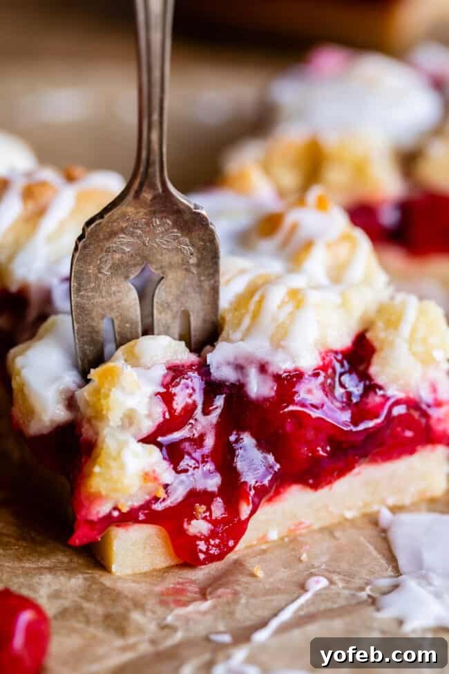 A close-up view of the rich and buttery shortbread base, glistening with cherry pie filling and ready for its crumble topping.