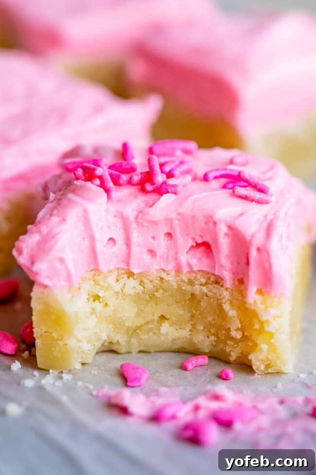 Soft and Chewy Sugar Cookie Bars from The Food Charlatan. These soft and chewy Sugar Cookie Bars are the stuff of dreams!! Adapted from my all time favorite soft sugar cookie recipe, these bars have a secret ingredient that make them supremely chewy. The thick layer of buttercream frosting on top makes them irresistible! #sugar #sugarcookie #bars #cookiebars #easy #recipe #withfrosting #best #buttercream #valentines #cookie #soft #chewy #icing #frosting sugar cookie bars recipe - close up of a soft and chewy bar with sprinkles