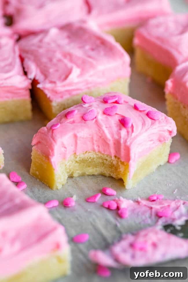 The secret is in the cream cheese. It doesn't go in the frosting! It replaces some of the butter usually called for in the sugar cookies. The cream cheese makes the final baked cookie supremely chewy and moist. sugar cookie bars recipe - a close-up of a stack of frosted bars