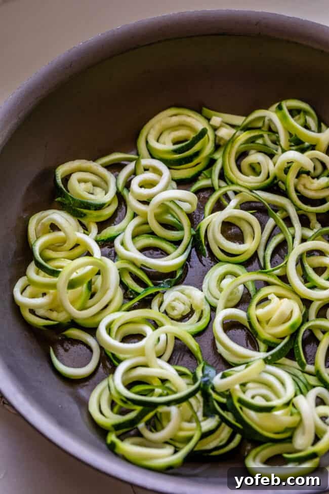 Spiralizer-Free Zucchini Noodles 16 Curly zucchini noodles sizzling in a hot frying pan, illustrating the sautéing process.