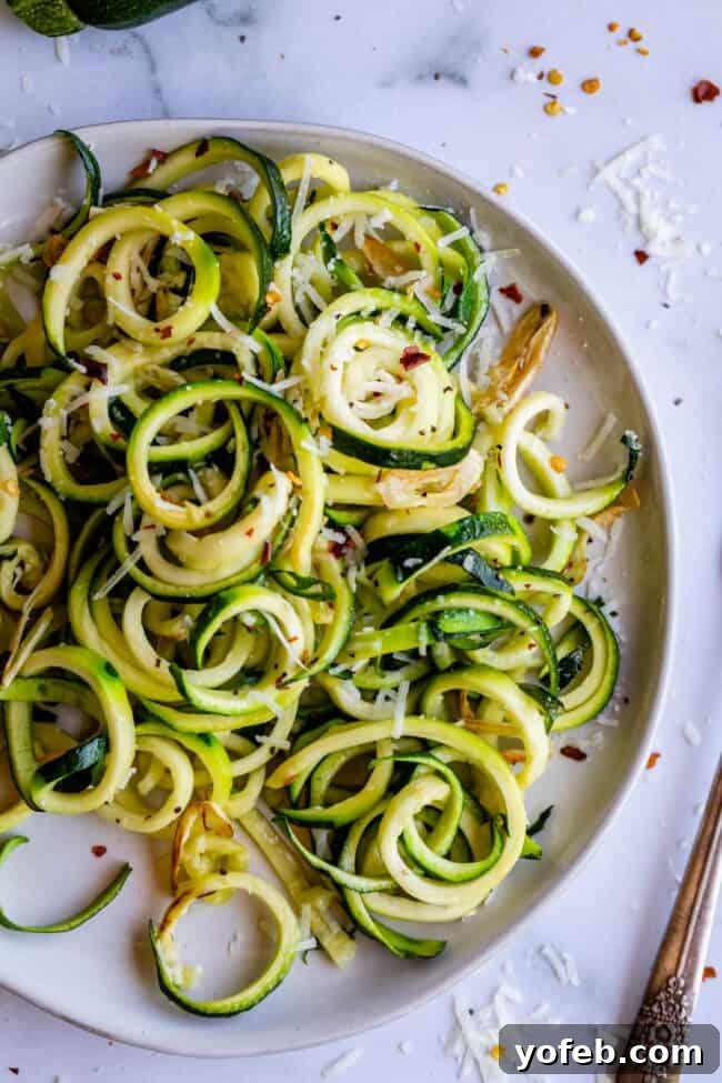 Spiralizer-Free Zucchini Noodles 18 A dish of vibrant zucchini noodles served on a white plate, seasoned with herbs and grated cheese.