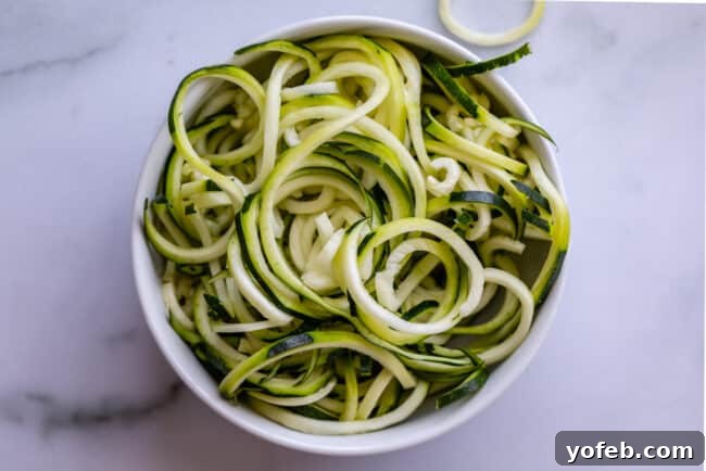 Spiralizer-Free Zucchini Noodles 7 A crisp white bowl filled with curly zucchini noodles, freshly made and ready for cooking.