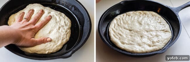 Carefully pressing pizza dough into a well-oiled cast iron skillet, ensuring it reaches the edges for a perfect crust.