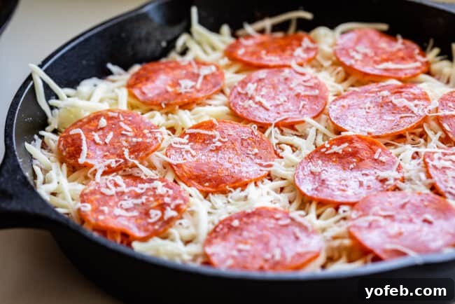 Arranging savory pepperoni slices over the cheese on a pizza in a skillet, prior to baking.