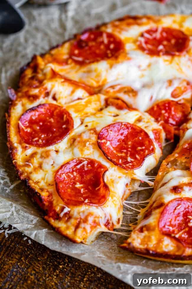 Thick-crusted pan pizza, perfectly cut into slices and arranged on parchment paper, highlighting its inviting texture.