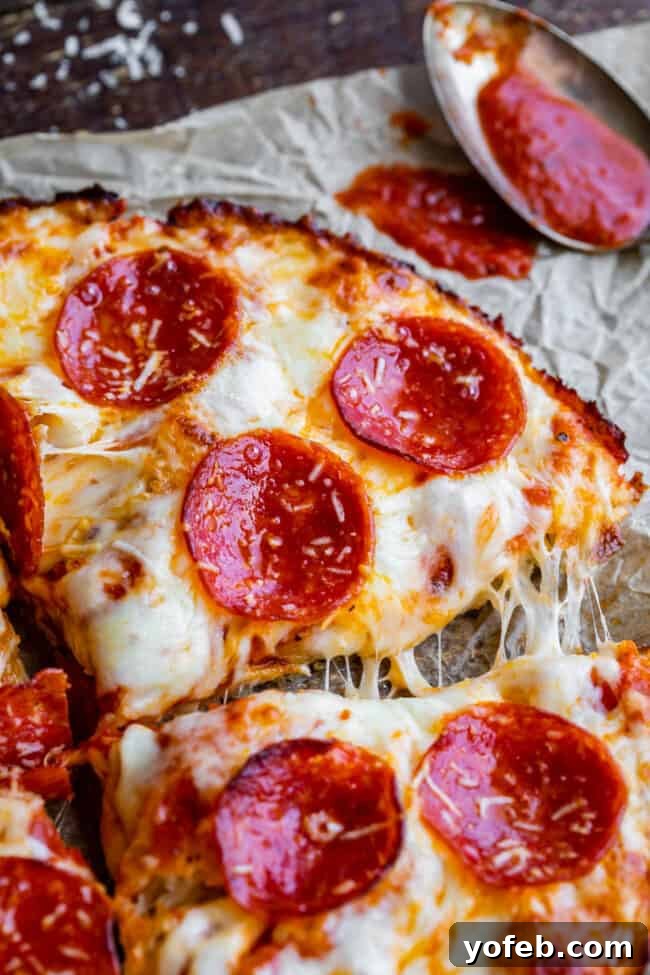 A freshly baked Pizza Hut style pan pizza, expertly sliced and presented on parchment paper, ready to be served.