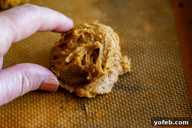 Visual guide: using two spoons to form soft pumpkin cookies, ensuring consistent size. Hands demonstrating the ideal size for soft pumpkin cookies using two spoons