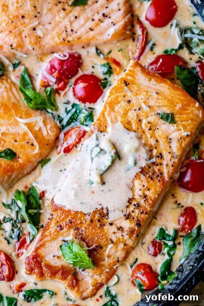Creamy Tuscan Salmon (30 Minute Dinner!) from The Food Charlatan. This Creamy Tuscan Salmon recipe is totally restaurant quality, but super easy to make! Perfectly pan-seared salmon, drowning in a creamy parmesan sauce with garlic, cherry tomatoes, spinach, and fresh basil. It's the perfect summer meal and is done in 30 minutes! #easy #recipe #summer #garden #salmon #tuscan #creamy #cherrytomato #basil #spinach #parmesan #tomato #30minutedinner #oneskillet #garlic #butter #garlicbutter #pasta a perfectly cooked creamy Tuscan salmon dish, garnished with fresh basil, ready to be served.