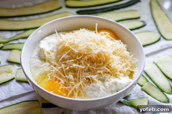 A pristine white bowl filled with a creamy ricotta mixture, featuring ricotta cheese, beaten eggs, and shredded Parmesan cheese, ready to be incorporated into the zucchini lasagna. This image emphasizes the rich, smooth texture of the cheese blend, a crucial element for a delicious and well-structured lasagna.