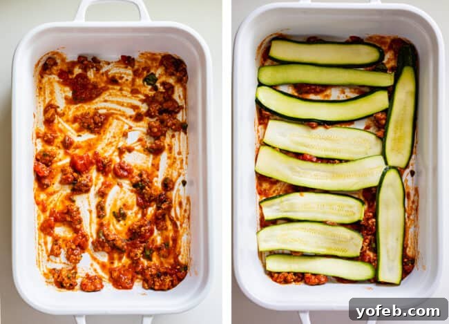 A white casserole dish with a base layer of red marinara sauce, topped with a single layer of thinly sliced zucchini noodles. This is the initial step in assembling a delicious low-carb zucchini lasagna, showcasing the neat arrangement of zucchini before the cheese and meat layers are added.