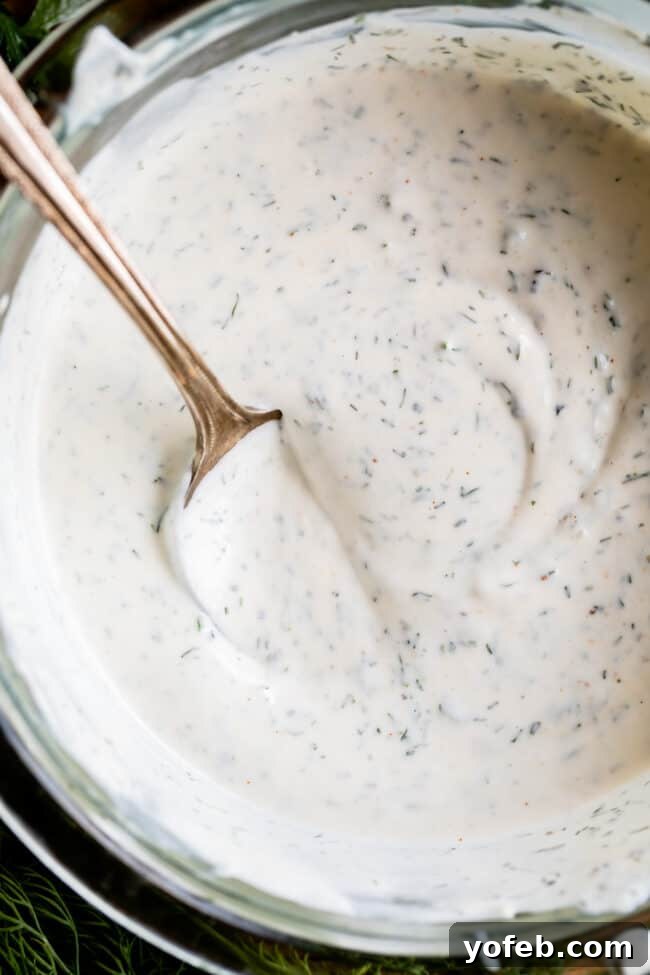 Homemade Buttermilk Ranch Dressing overhead shot of creamy buttermilk ranch dressing in a glass bowl with a spoon in it.