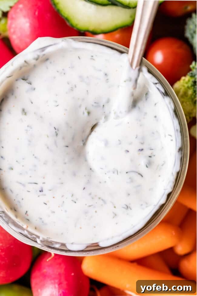 The Ultimate Homemade Buttermilk Ranch Dressing 2 homemade buttermilk ranch dressing in glass jar with a spoon in it surrounded by vegetables.