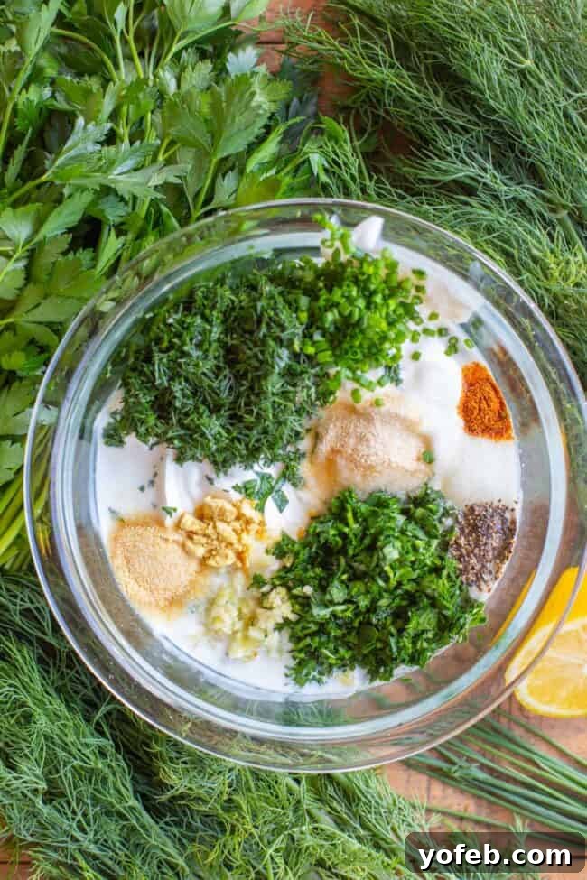 Homemade Buttermilk Ranch Dressing fresh herbs and spices being added to dressing in glass jar surrounded by fresh herbs and lemons.