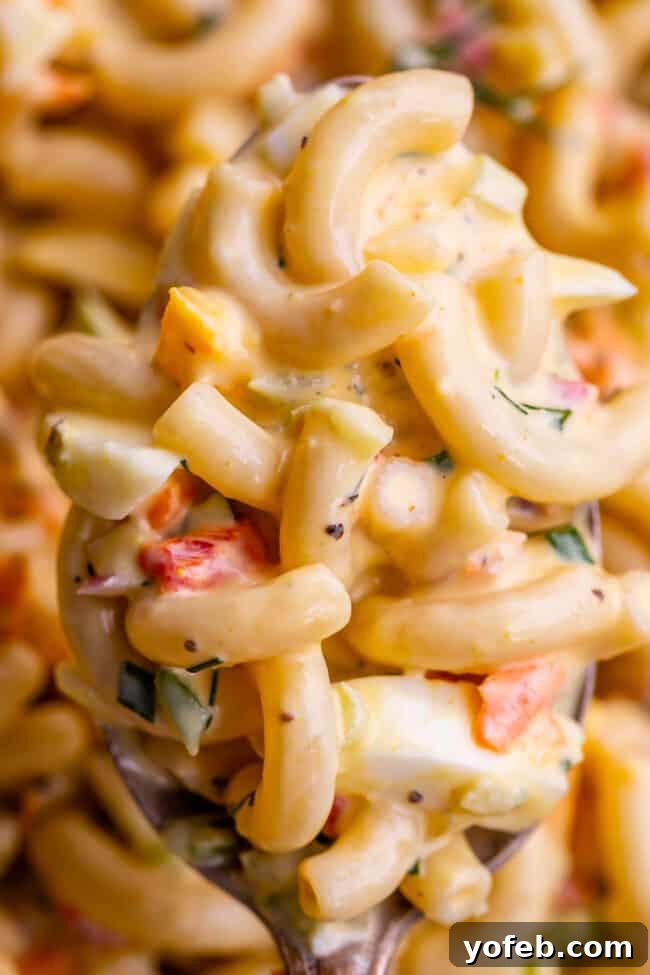 Classic Creamy Macaroni Salad 3 close-up of creamy macaroni salad on a serving spoon, highlighting the rich texture and colorful, finely diced vegetables.