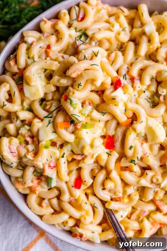 Classic Creamy Macaroni Salad 4 best macaroni salad recipe in a large serving bowl with a spoon, ready to be enjoyed.