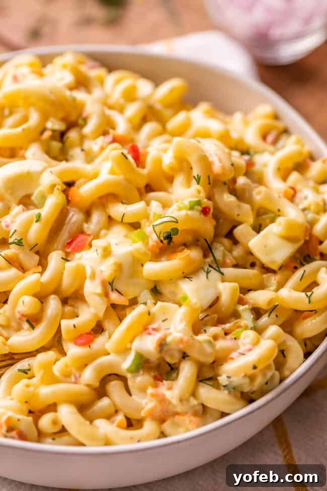 Classic Creamy Macaroni Salad 7 creamy macaroni salad with visible chopped hard-boiled eggs in a bowl, emphasizing its rich texture.