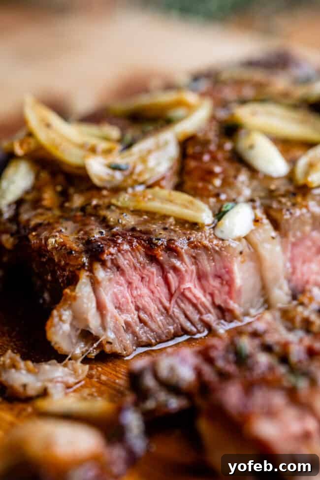 Perfectly sliced ribeye steak recipe showing off its juicy, medium-rare interior, drizzled with garlic butter.