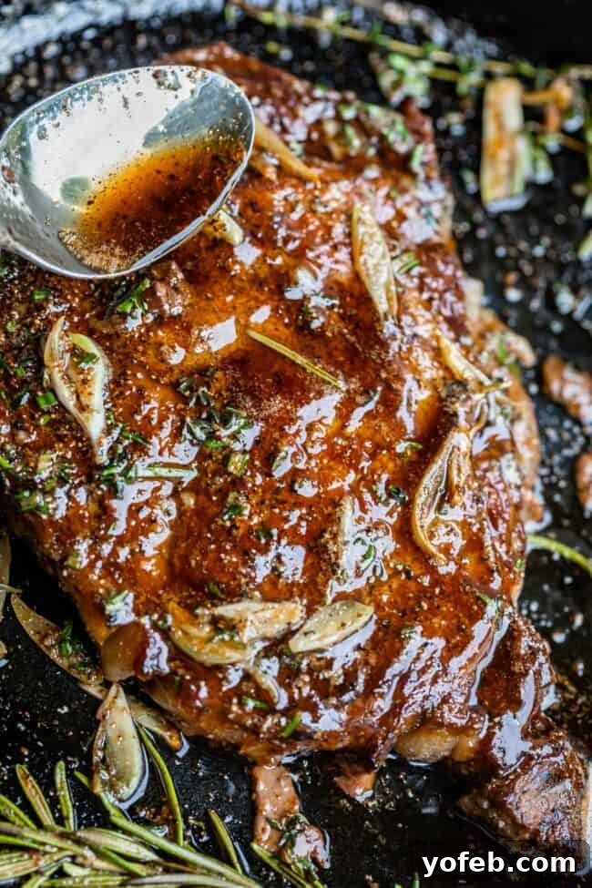 Grilled ribeye steak with melted garlic butter, garnished with fresh thyme and rosemary.