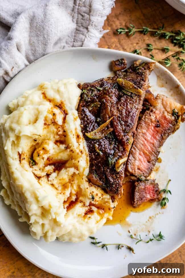 Delicious ribeye steak on a plate, served with a generous scoop of creamy mashed potatoes and melted garlic butter.