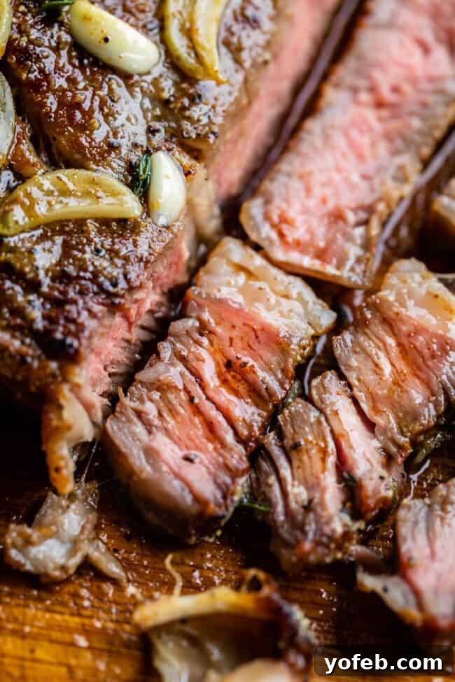 Juicy grilled ribeye steak, expertly sliced on a wooden cutting board, drenched in melted garlic butter.