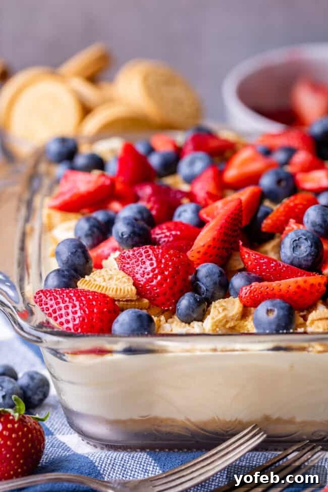 4th of July Layered Pudding Dessert with Golden Oreos from The Food Charlatan. It is a popular dessert for good reasons: it is super easy, it feeds a crowd, it's no bake, and it's so good! I made it with Golden Oreos layered with vanilla pudding, topped with strawberries and blueberries. Such an easy and festive dessert for 4th of July! #easy #recipe #pudding #lush #delight #layered #dessert #torte #strawberries #blueberries #yummy #dreamcake #dirtpudding, #oreo #coolwhip #4thofJuly #patriotic Red, White, and Blue Vanilla Pudding Dessert
