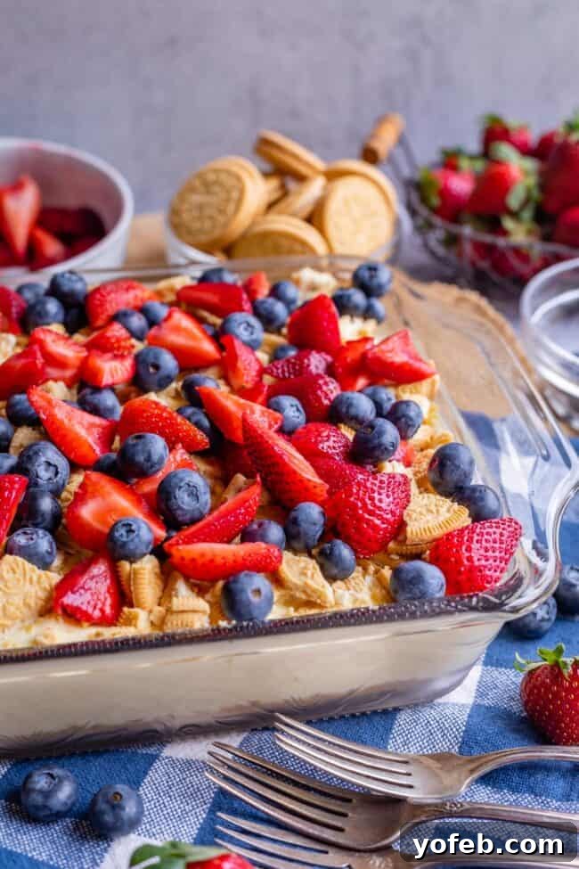4th of July Layered Pudding Dessert with Golden Oreos from The Food Charlatan. It is a popular dessert for good reasons: it is super easy, it feeds a crowd, it's no bake, and it's so good! I made it with Golden Oreos layered with vanilla pudding, topped with strawberries and blueberries. Such an easy and festive dessert for 4th of July! #easy #recipe #pudding #lush #delight #layered #dessert #torte #strawberries #blueberries #yummy #dreamcake #dirtpudding, #oreo #coolwhip #4thofJuly #patriotic Layered Pudding Dessert with Blueberries and Strawberries