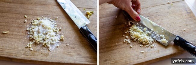 Garlic Aioli Recipe (Classic and Cheater Versions) from The Food Charlatan. I will show you just how easy it is to make homemade Garlic Aioli Sauce! Making it from scratch is quick and easy, but I have a cheater version that is even quicker and easier. Either way you make it, aioli is lemony garlicky heaven! It will be your new favorite condiment in no time. #recipe #easy #garlic #lemon #aioli #sauce #mayonnaise #roasted #garlicmayo #fromscratch #homemade #creamy A chef's knife being used to crush kosher salt into finely minced garlic on a cutting board, forming a paste.