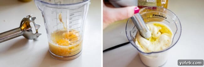 Garlic Aioli Recipe (Classic and Cheater Versions) from The Food Charlatan. I will show you just how easy it is to make homemade Garlic Aioli Sauce! Making it from scratch is quick and easy, but I have a cheater version that is even quicker and easier. Either way you make it, aioli is lemony garlicky heaven! It will be your new favorite condiment in no time. #recipe #easy #garlic #lemon #aioli #sauce #mayonnaise #roasted #garlicmayo #fromscratch #homemade #creamy An immersion blender being used to emulsify ingredients in a tall glass container, making garlic aioli.