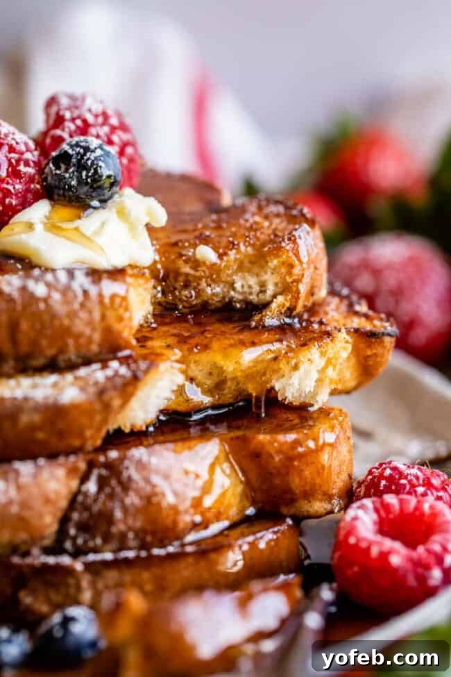 Golden Glazed French Toast 17 Thick and fluffy French toast stacked on a plate with butter, syrup, and fresh berries.
