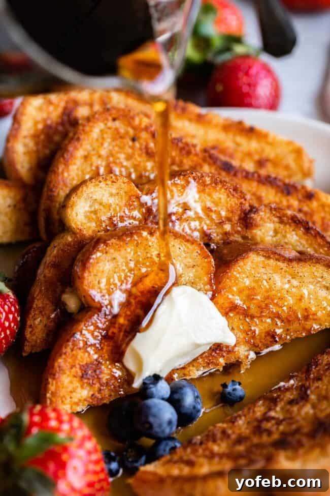 Golden Glazed French Toast 3 Stack of French toast with syrup, strawberries, and blueberries.