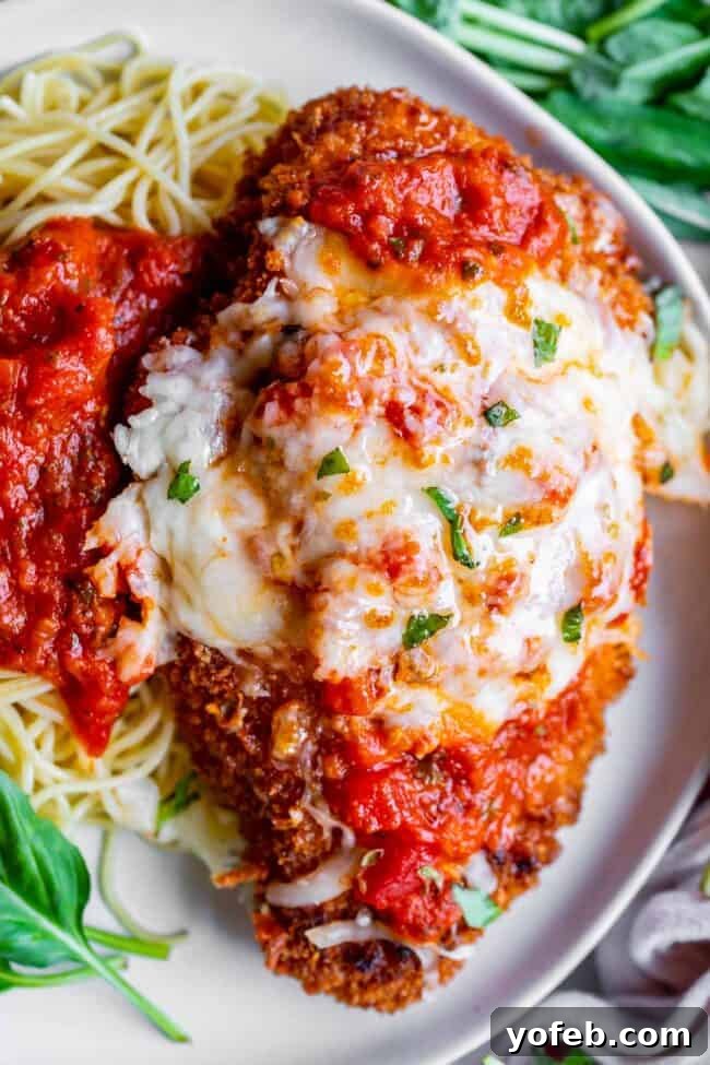 Heavenly Chicken Parmesan 15 crispy parmesan chicken on a plate with pasta and marinara sauce.