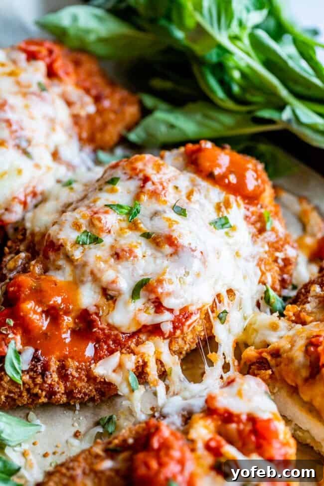 Heavenly Chicken Parmesan 3 melty cheese pull on the side of breaded chicken parmesan.