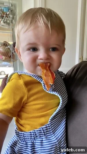 Creamy Homemade Velveeta Mac and Cheese 4 An adorable baby boy, happily tasting a strip of bacon, illustrating a moment of curiosity and exploration.