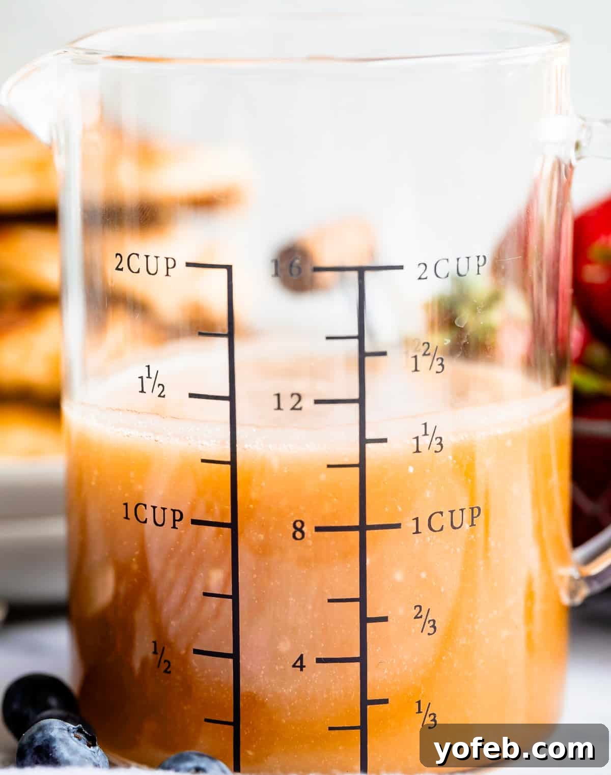 Velvet Smooth Buttermilk Syrup 3 Buttermilk syrup in a glass measuring cup with blueberries in the foreground.