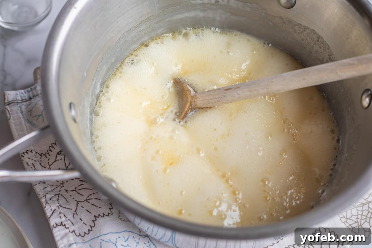 Velvet Smooth Buttermilk Syrup 9 a metal pot of yellow boiling liquid with a wooden spoon.