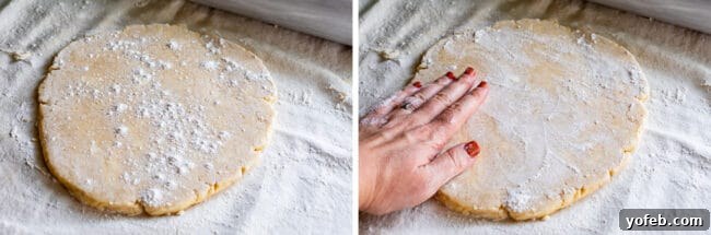 A hand sprinkling flour over pie dough to prevent sticking during the rolling process.