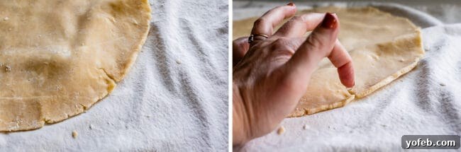 A hand using ice water to carefully fix a crack on pie dough, demonstrating a repair technique during rolling.
