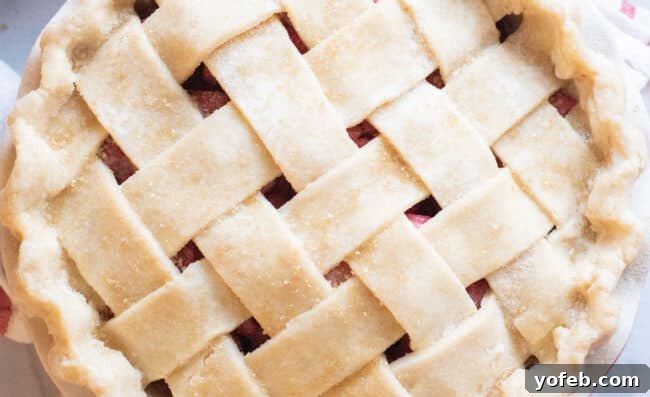 Raw sugar is generously sprinkled on a lattice pie crust, adding a sweet sparkle before baking.