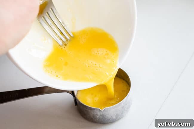A person pouring beaten egg into a 1/4 cup measuring cup, a precise step for making tender pie dough.
