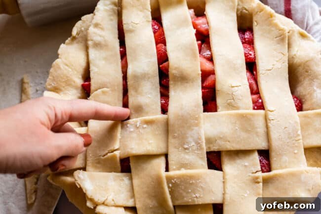 A Visual Guide to Making a Lattice Pie Crust 11 finger pointing to the next strip of pie dough that needs to be pulled back for lattice crust