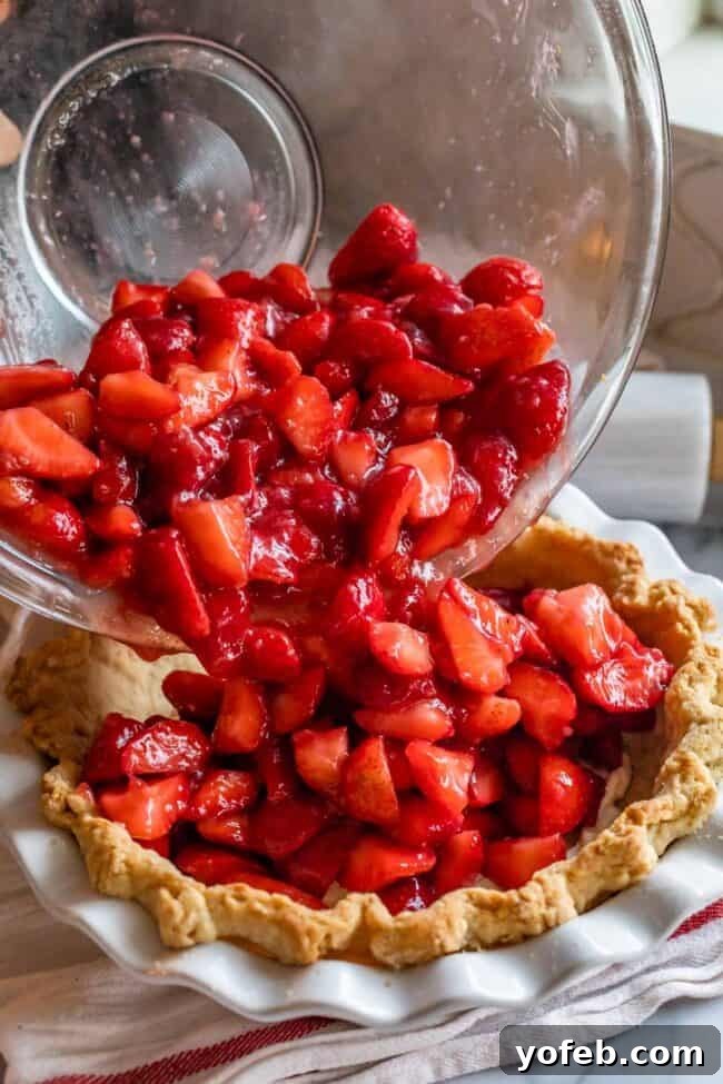 How to Pre-Bake Your Pie Crust Perfectly 13 Fresh, vibrant strawberries being carefully poured into a perfectly pre-baked pie shell, ready to create a classic strawberry glacé pie.
