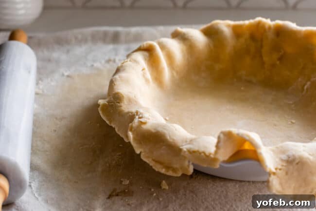 How to Pre-Bake Your Pie Crust Perfectly 4 A raw pie dough, perfectly rolled out and placed within a pie pan, showing the initial preparation stage before blind baking begins. The edges are neatly trimmed and ready for crimping.