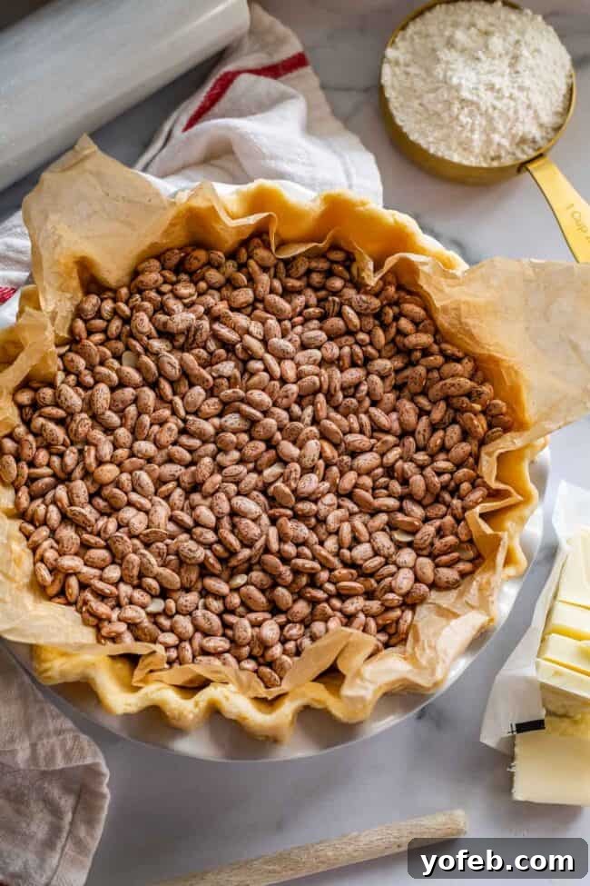 How to Pre-Bake Your Pie Crust Perfectly 8 A raw pie dough in a pan, meticulously filled with a generous amount of dry beans serving as pie weights, ensuring even pressure and preventing shrinkage during blind baking.