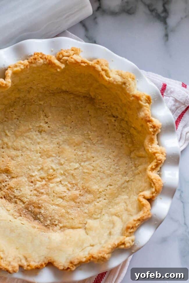 How to Pre-Bake Your Pie Crust Perfectly 9 An overhead view of a partially blind-baked pie crust, showing a flat bottom with faint pricks from a fork, and lightly golden edges, ready for the next baking stage.