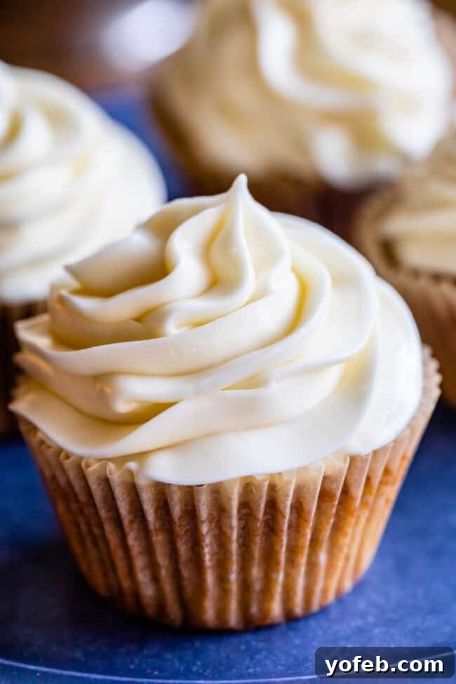 The Ultimate Cream Cheese Frosting 10 A delicious homemade cream cheese frosted cupcake on a blue plate, ready to be enjoyed.