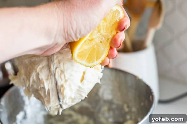 The Ultimate Cream Cheese Frosting 7 Fresh lemon juice being squeezed into the mixer with cream cheese frosting.