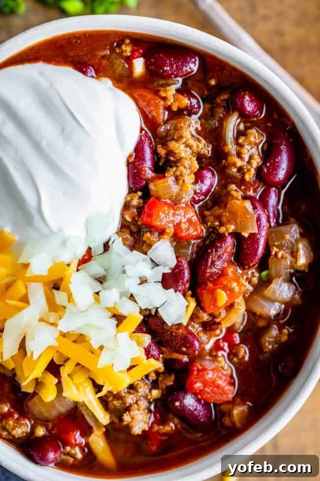 Effortless 45 Minute Chili 5 basic chili recipe in a white bowl garnished with sour cream, cheese, onions.