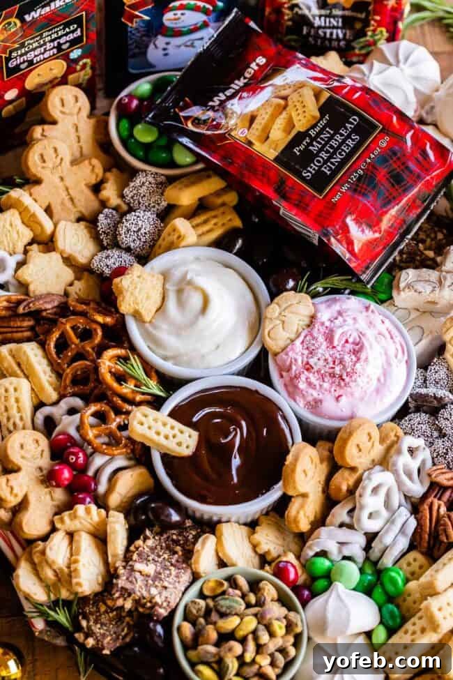 Sweet Grazing Boards 4 A bountiful dessert charcuterie board for Christmas, featuring Walkers Shortbread, crunchy pretzels, sweet toffee, and colorful candies, all artfully arranged around a trio of dips.