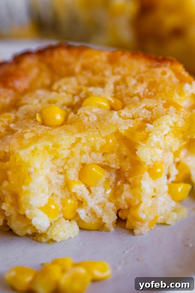 Golden Cornbread Delight 2 creamed corn casserole on a plate with a bite taken out.