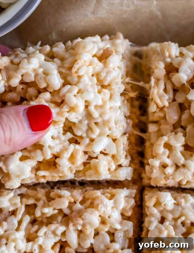 Foolproof Rice Krispies Treats 6 Hand pulling a soft, stretchy Rice Krispie Treat from the pan.